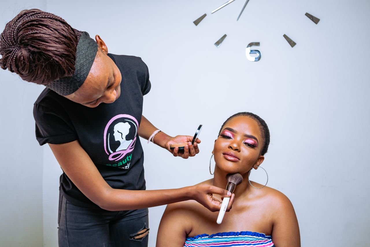 A makeup artist skillfully applies cosmetics to enhance her client's beauty in a salon setting.