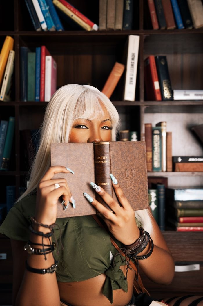 Smiling woman holding a book in a cozy library, creative and inspiring ambiance.